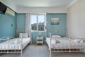 Ein Schlafzimmer mit zwei Betten, einem Fenster, einer Lampe und einem Bild an der Wand.