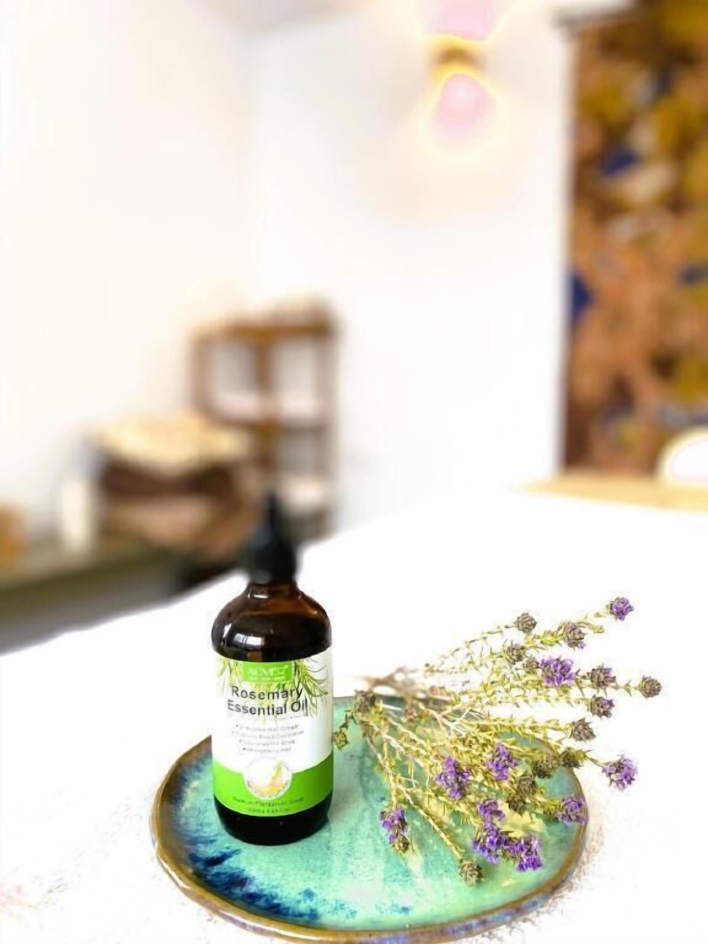 Una botella de aceite esencial de romero sobre un plato verde azulado con flores secas.