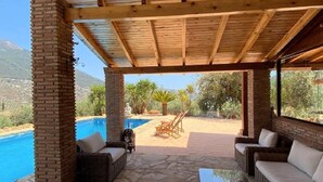 Un espace extérieur abrité, doté d’une piscine, de meubles en osier et offrant une vue sur le paysage.