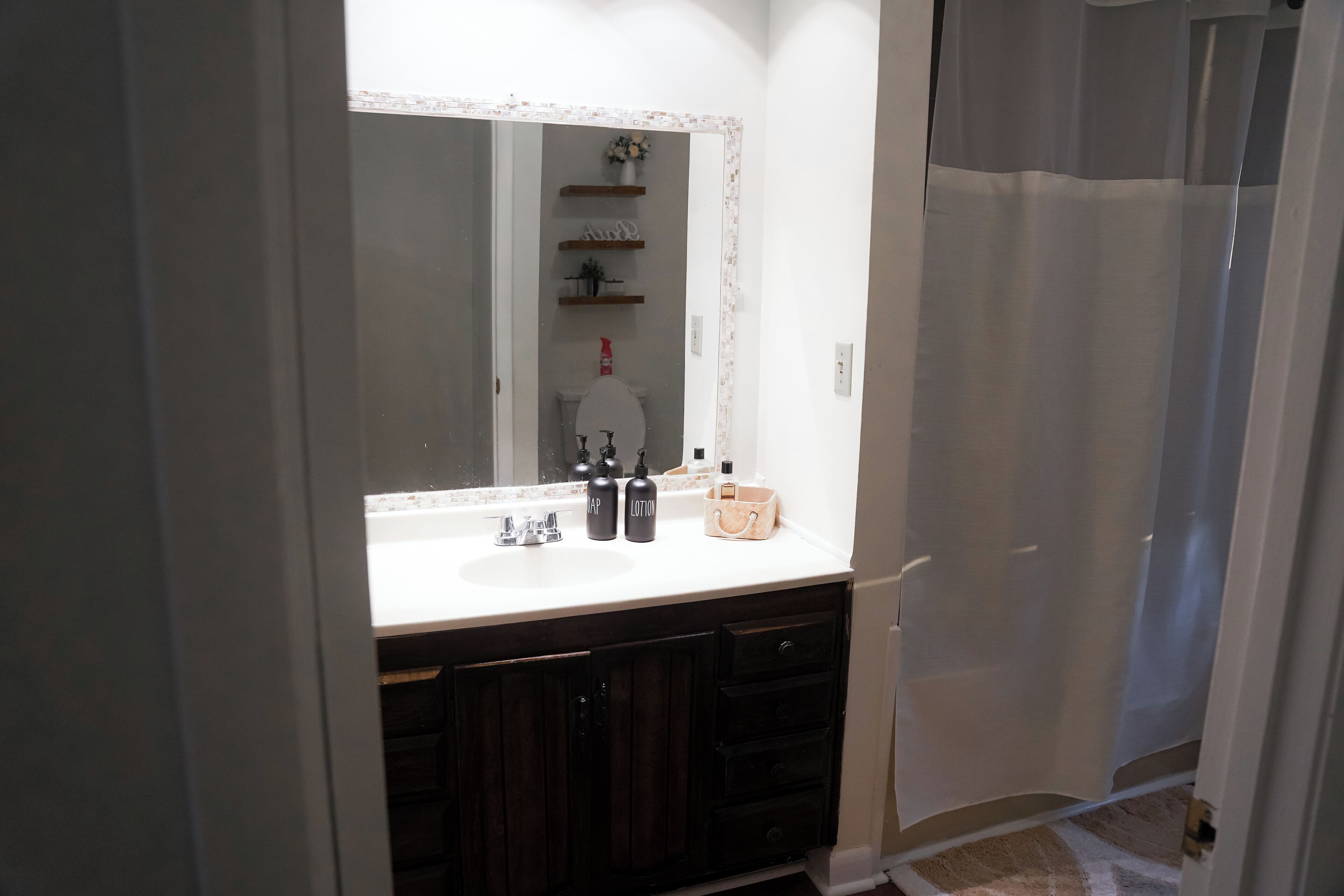 Une salle de bain avec un lavabo blanc, des meubles en bois foncé et un grand miroir.