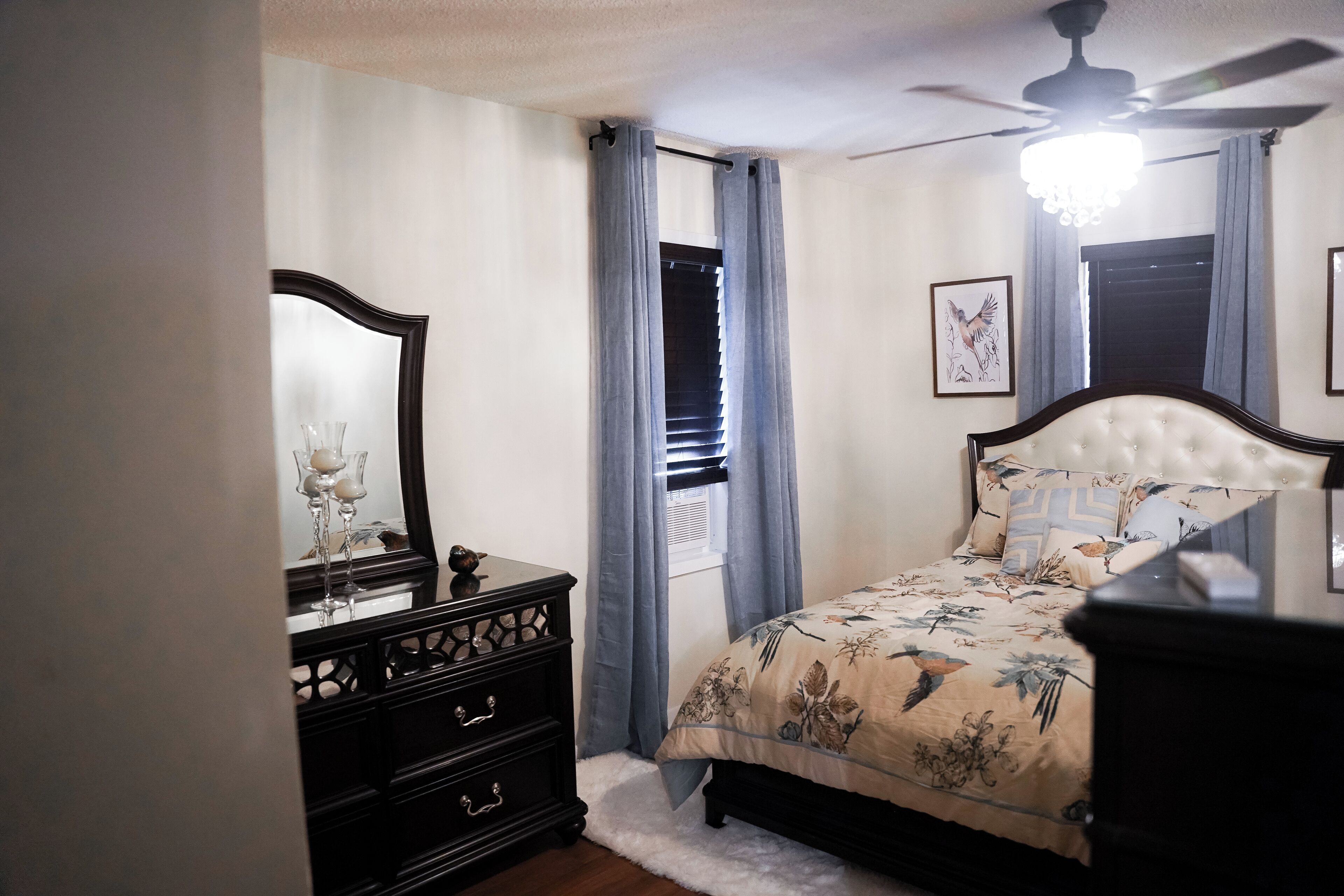 Un dormitorio con cama, cómoda, espejo y ventilador de techo.