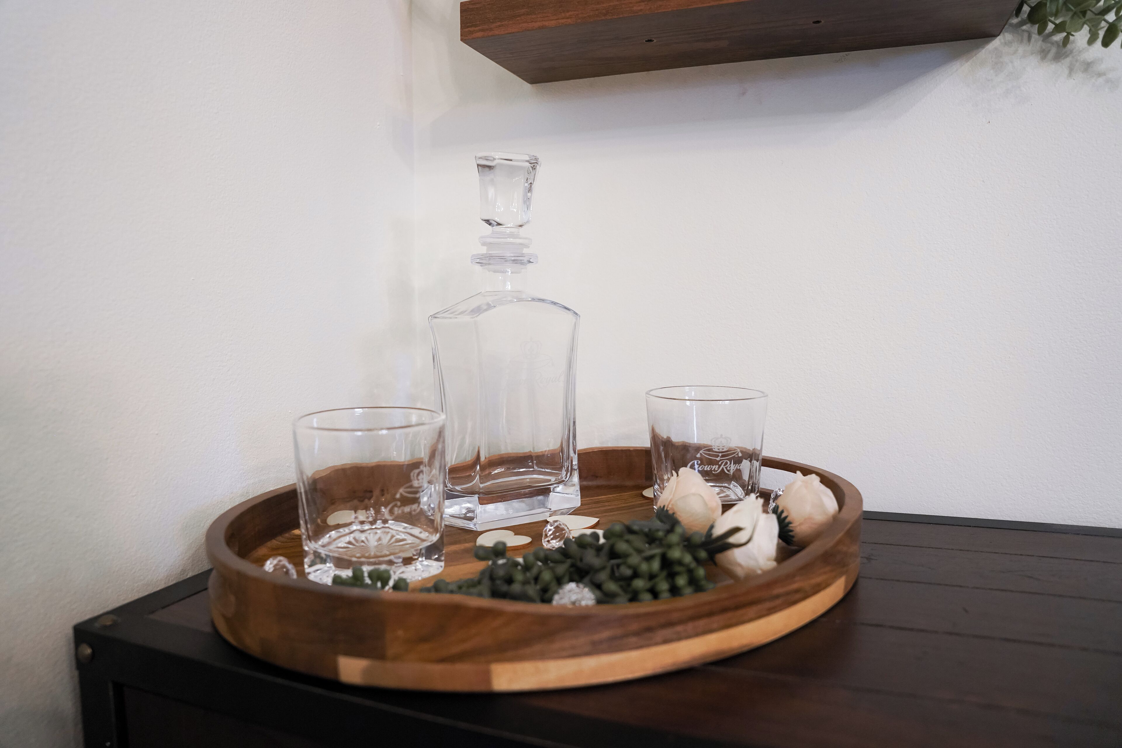 A wooden tray with a decanter and two glasses on a table.