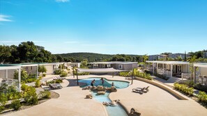 Ein Poolbereich mit Liegestühlen, einer kleinen Wasserfallanlage und Blick auf die umliegende Landschaft.