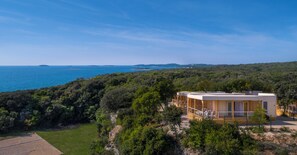 Una cabaña moderna con terraza y vistas al paisaje costero.