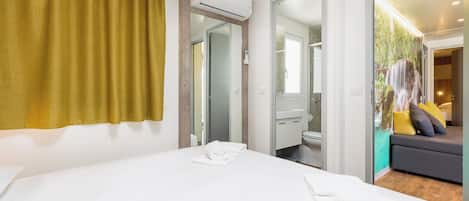 Una habitación de hotel con cama, baño y sala de estar con sofá y cojines.