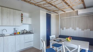 Eine moderne Küche mit weißen Schränken, einem eingebauten Herd und einem Essbereich mit weißem Tisch und blauen Stühlen.