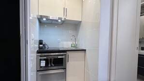 Een kleine keuken met roestvrijstalen apparatuur, een inbouwoven en een spoelbak.