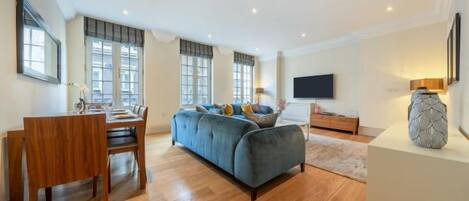 A spacious living room with a sofa, a dining table, and a TV.
