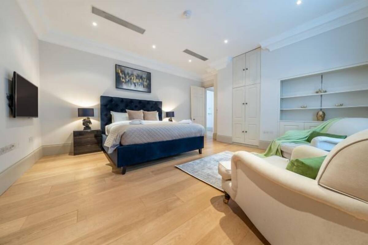 Une chambre à coucher avec un lit, des tables de chevet, une télévision, un tableau et une armoire.