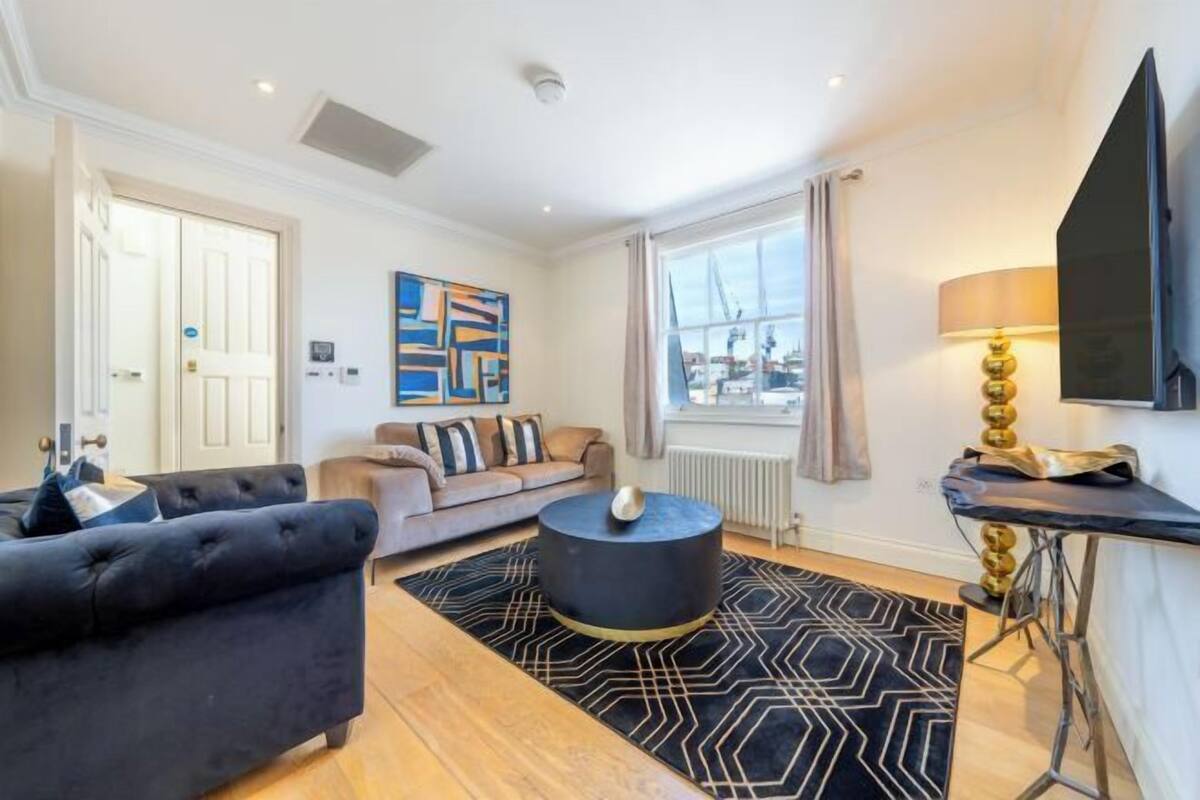 Un salon moderne avec un canapé bleu foncé, une table basse ronde et un tapis à motifs géométriques.