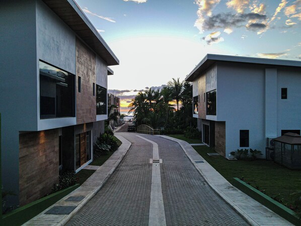 A modern building with a curved driveway, large windows, and a view of the sunset. - Double the space, double the fun ! 2 Brand New Luxury Villas, Gated Community (Jaco)