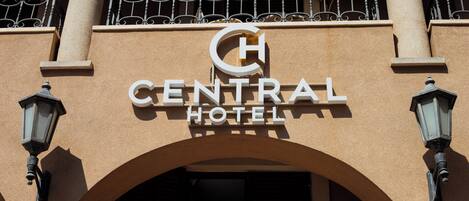 Exterior del Hotel Central con un letrero llamativo, entrada en arco y barandillas de hierro decorativas.