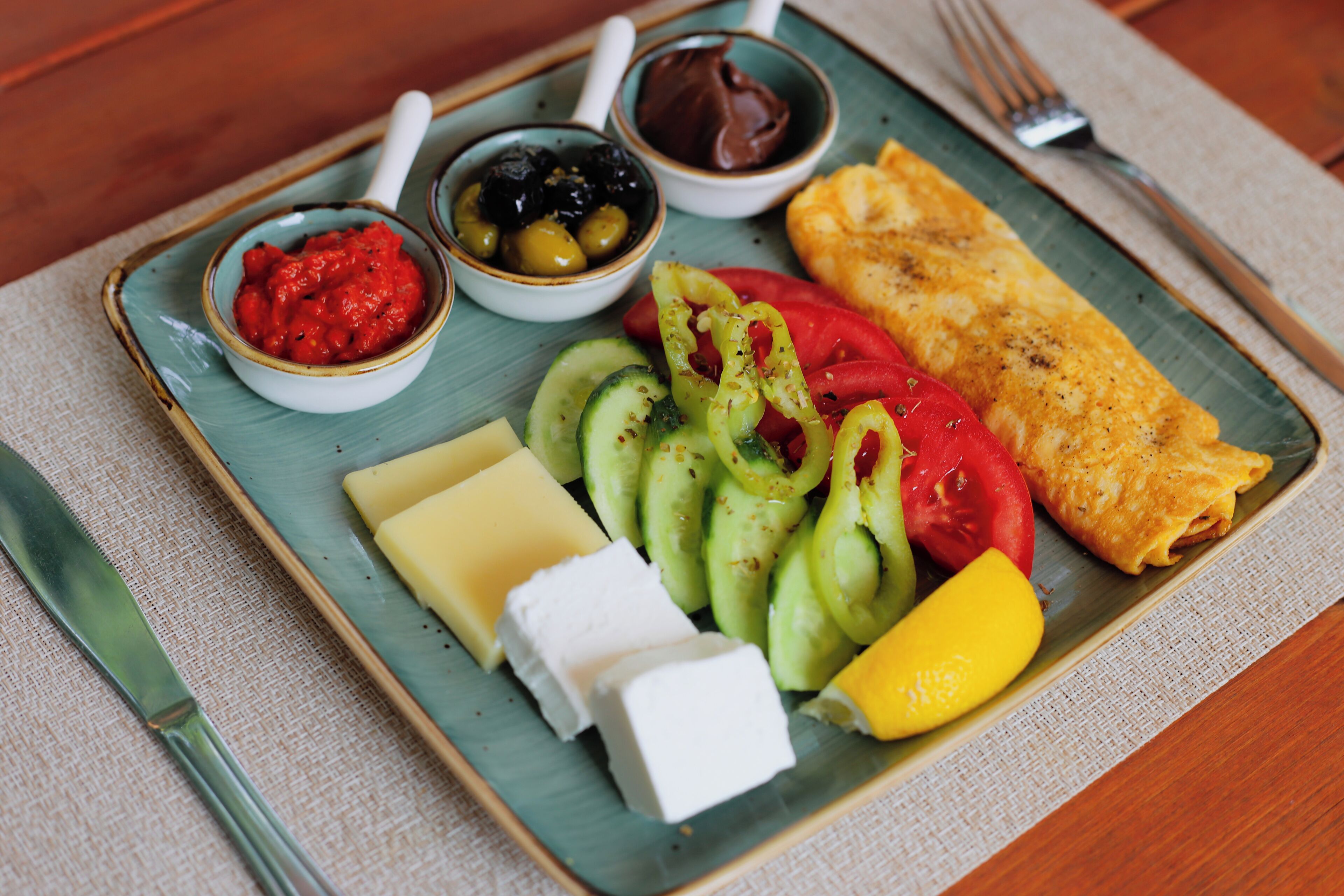 A plate with various food items including a piece of fish, cheese, vegetables, and condiments.