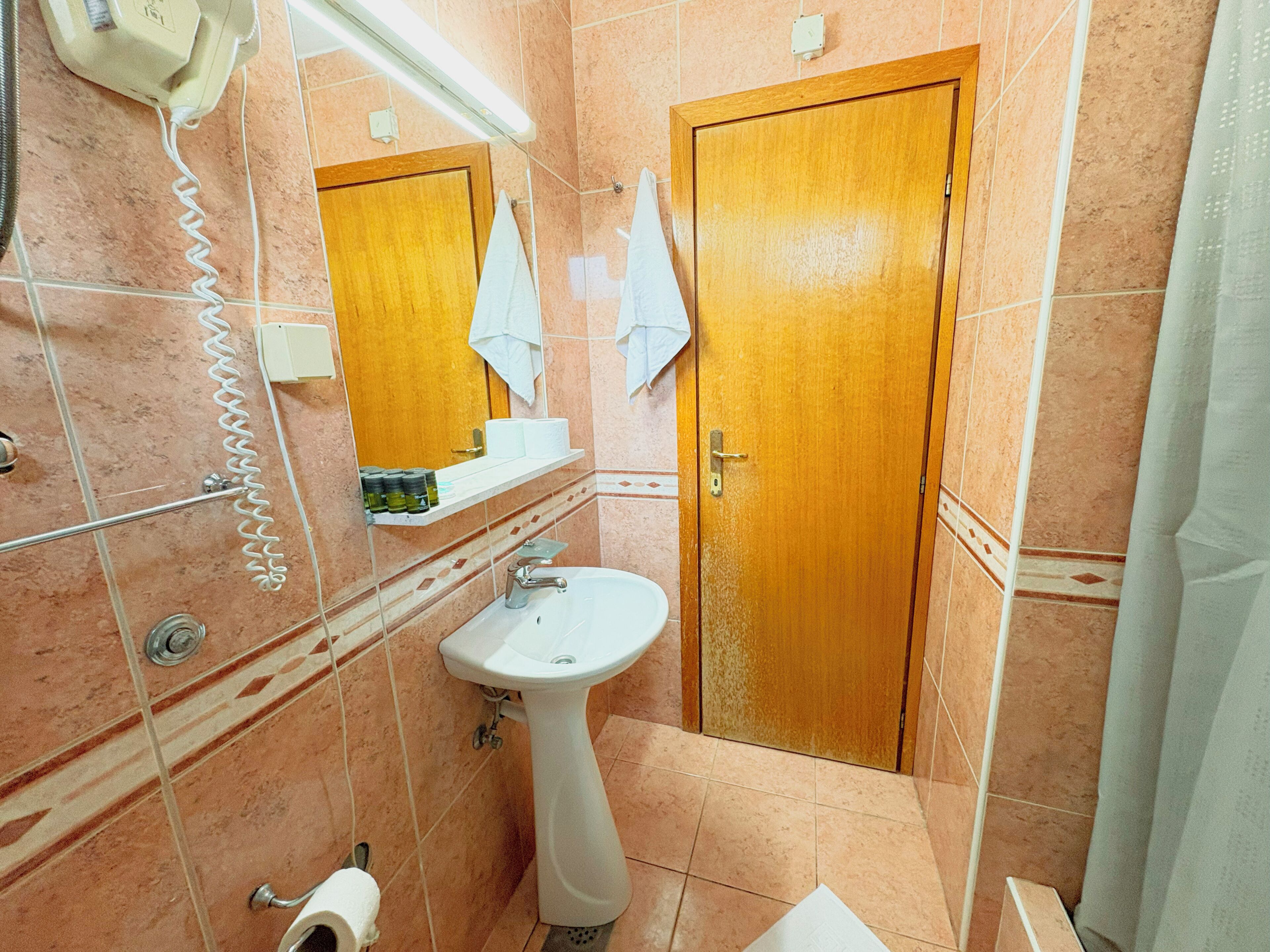 A bathroom with a sink, mirror, and wooden door.