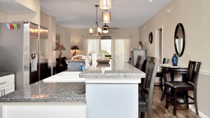 Uma cozinha moderna com ilha central, eletrodomésticos de aço inoxidável e iluminação pendente.