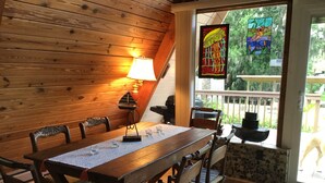 A wooden dining table with chairs, a lamp, and a stained glass window with a bird and a jellyfish design.
