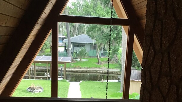 A room with a large window overlooking a backyard with a pathway, a gazebo, and a pond.