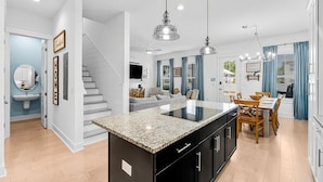 A modern kitchen with a central island, black cabinets, and pendant lighting. - 30A Beach House - Paradise Valle (Panama City Beach)