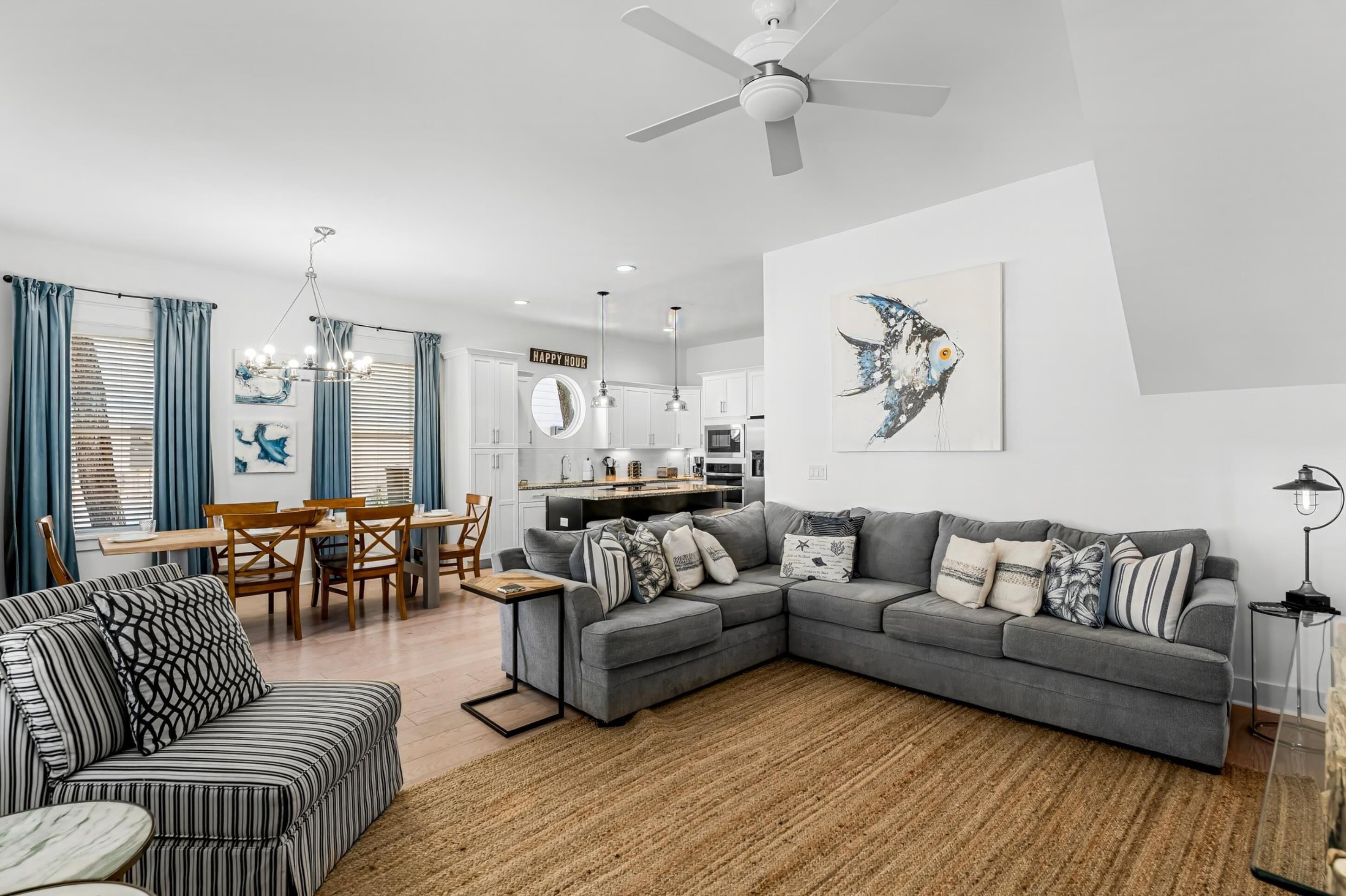 A modern living room with a grey sectional sofa, a striped armchair, and a dining area with a wooden table and chairs.