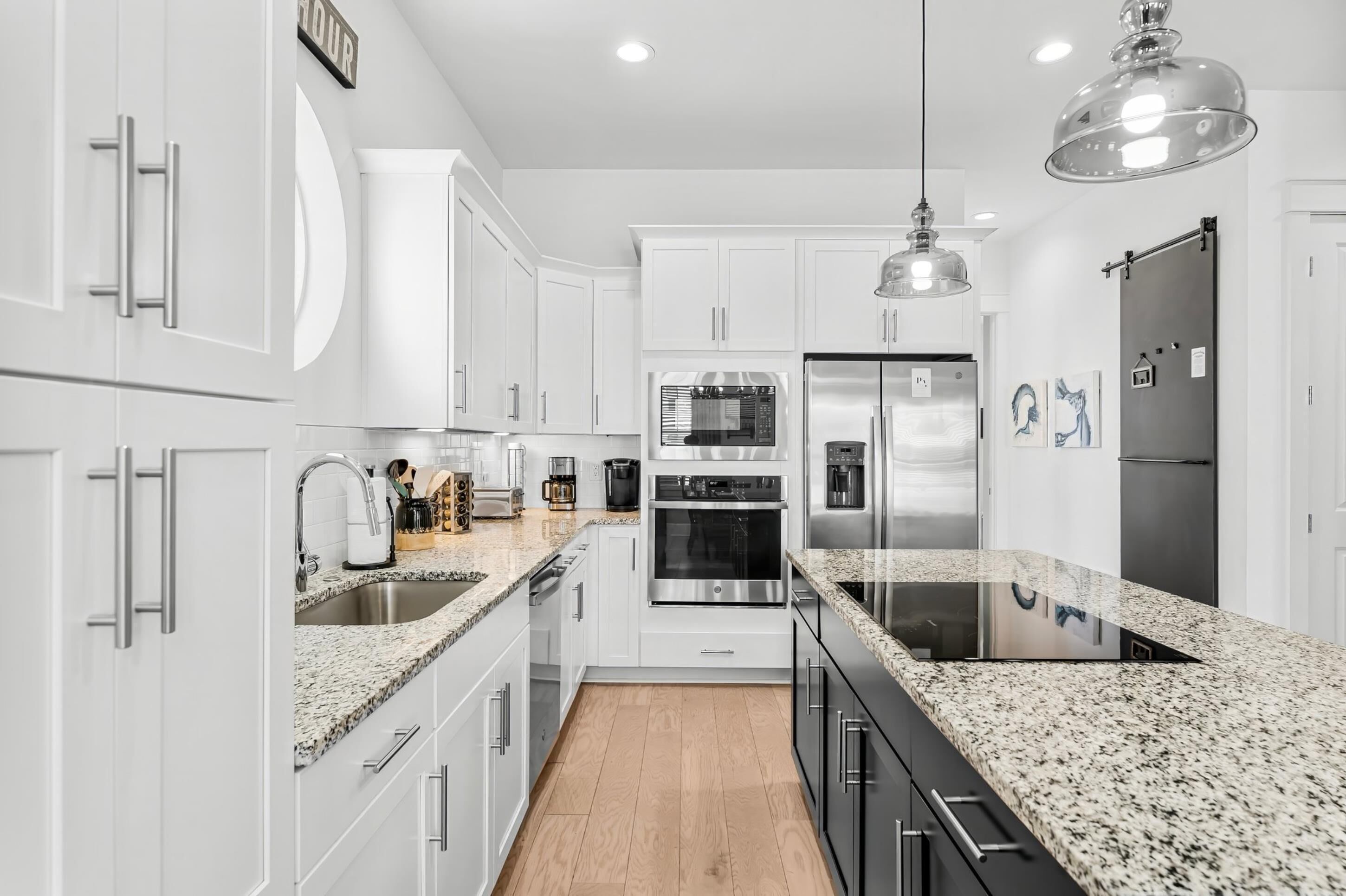 A modern kitchen with white cabinetry, granite countertops, stainless steel appliances, and a central island.