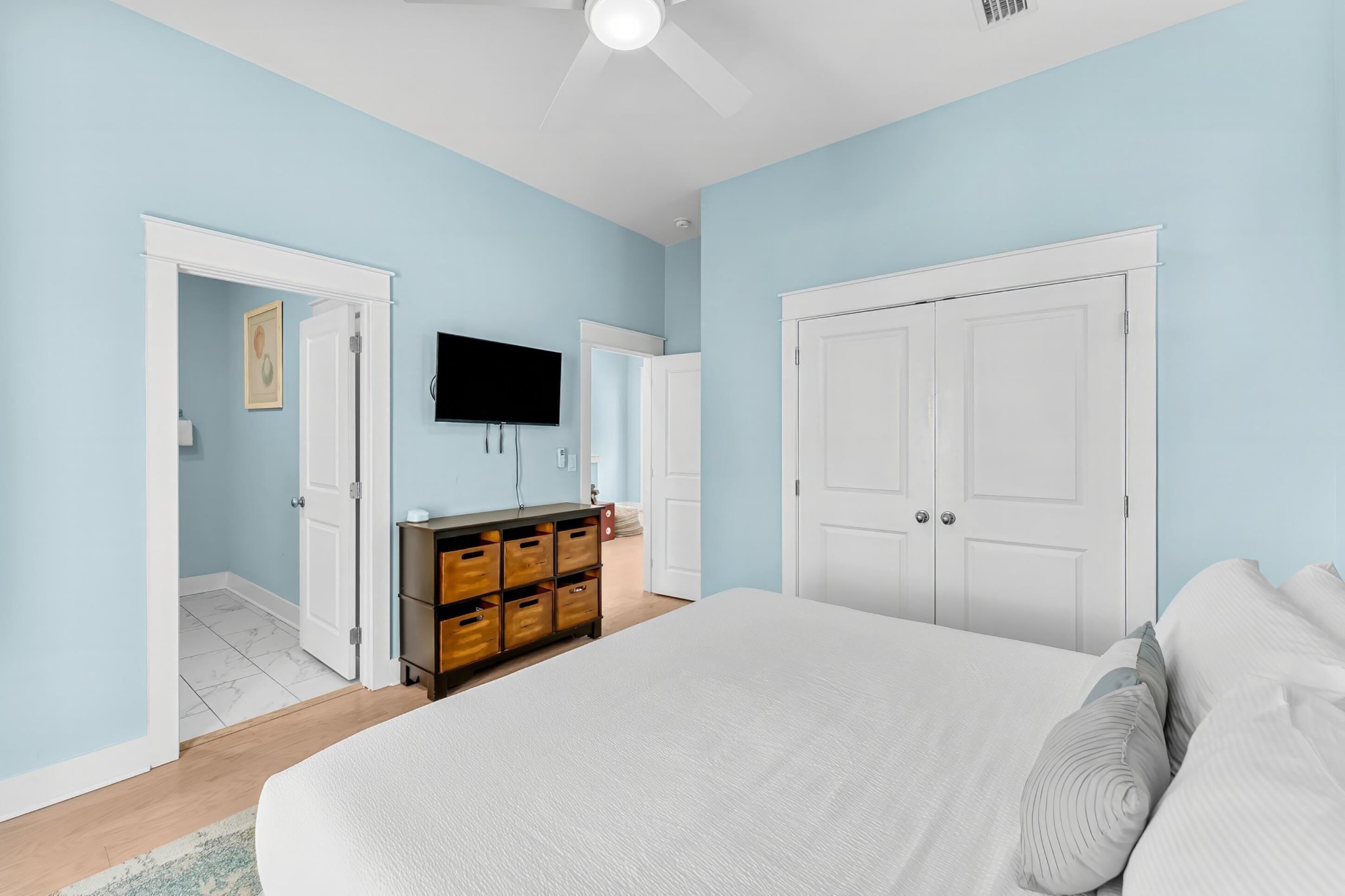 Une chambre à coucher avec un lit, une commode, un téléviseur et une porte.