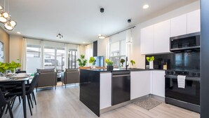 A modern kitchen with a central island, built-in appliances, and a dining area with chairs and a table. - Family Friendly w Pool Near Disney at Serenity 1420 (Clermont)
