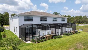 A modern two-story house with a large glass conservatory and a well-maintained lawn. - Family Friendly w Pool Near Disney at Serenity 1420 (Clermont)