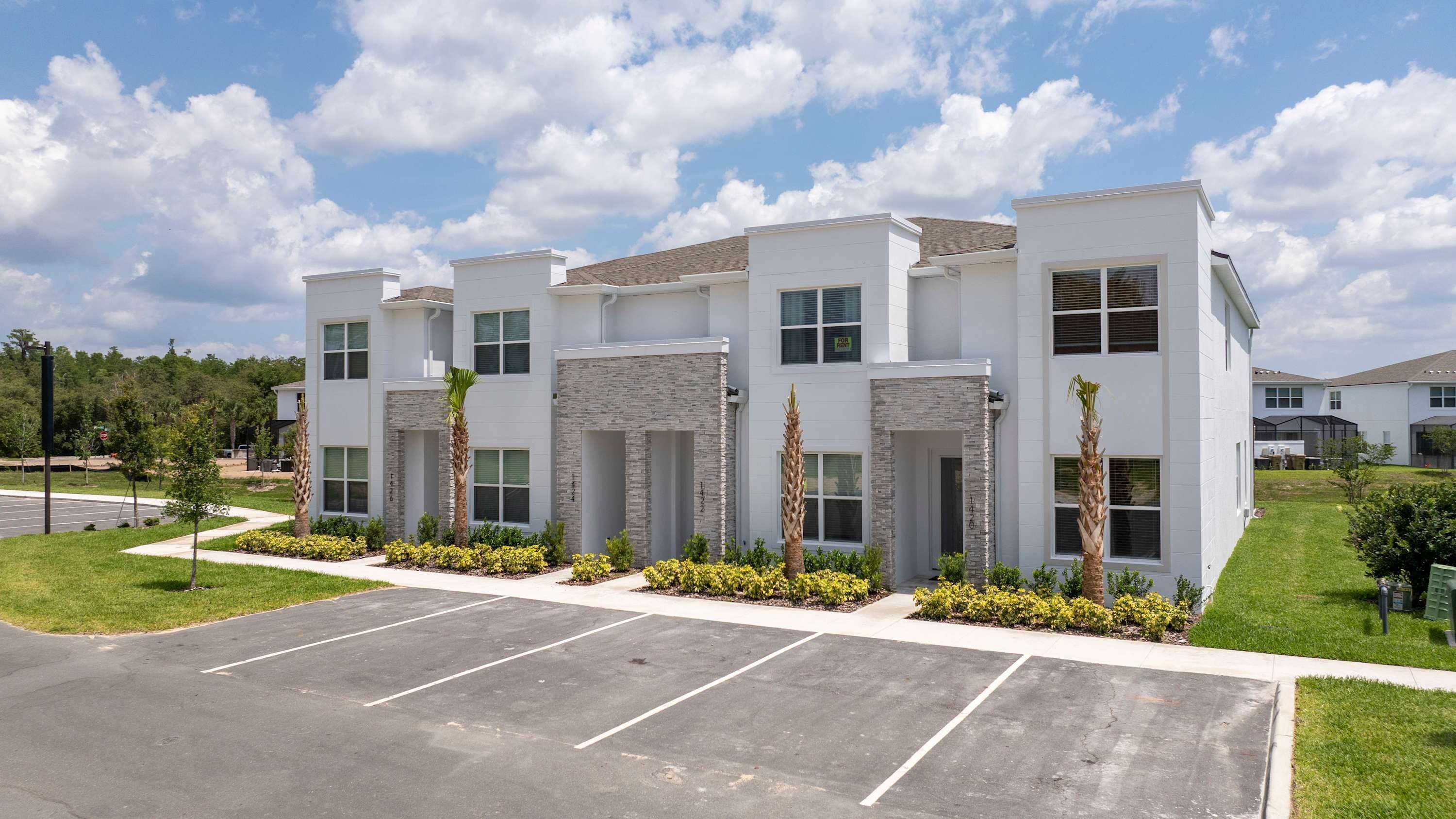 A modern multi-story building with a parking lot in front.