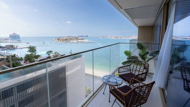Ein Balkon mit Blick auf einen Strand und ein Kreuzfahrtschiff.