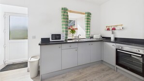 A modern kitchen with a microwave, sink, and oven. - Bathach Beag (Oban)