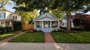 A two-story house with a porch, a swing, and a flag.