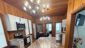 Una cocina amplia con paredes de madera, una isla central y una araña.