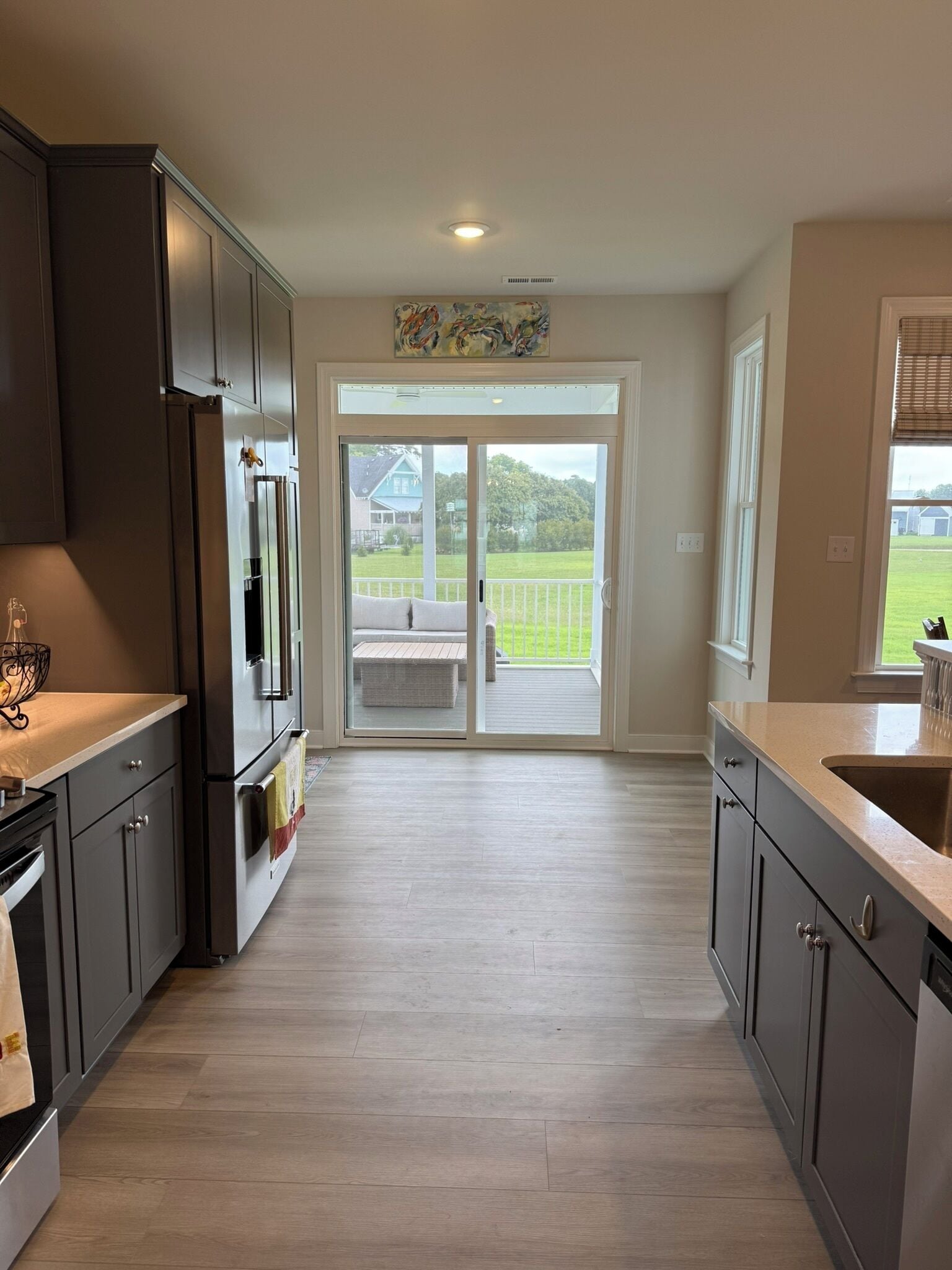 A modern kitchen with dark cabinets, stainless steel appliances, and a large sliding glass door leading to a balcony.