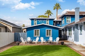 Una casa azul con un letrero que dice "Chelsea Place On The Park" y sillas blancas en el jardín.