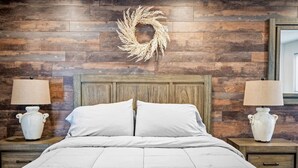 A bedroom with a wooden headboard, two bedside lamps, a white bedspread, and a decorative wreath on the wall. - 11 Chelsea Place On The Park, In Heart Of Downtown (Phoenix)