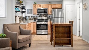 A modern kitchen with wooden cabinets, stainless steel appliances, and a dining area with a wooden table and chairs. - 11 Chelsea Place On The Park, In Heart Of Downtown (Phoenix)