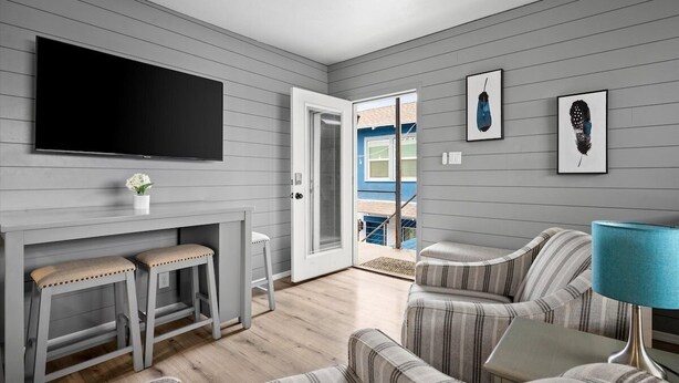Een moderne woonkamer met een flatscreen-televisie, gestreepte banken, een salontafel en een deur naar een balkon.