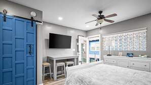Quarto com cama, escrivaninha, cadeira, televisão e porta deslizante azul.