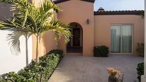 A building with a beige exterior, a tiled roof, a door, and a window.