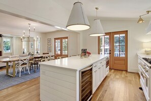A spacious kitchen with a large island, wooden flooring, and pendant lighting. - Old Village Luxury – Historic 5BR, Walk to Dining, Shops, & Sunset Views (Mount Pleasant)