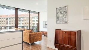 A modern apartment with a large window, a wooden cabinet, and a sofa. - Liiiving in Matosinhos - Warm Vintage Apartment (Matosinhos)