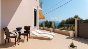A balcony with a table, chairs, a sun lounger, and potted plants. - La Casa Rosa Seaside Getaway (Dorida)
