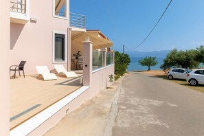 A pink building with a balcony, lounge chairs, and a view of the sea. - La Casa Rosa Seaside Getaway (Dorida)
