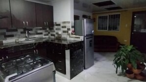 Una cucina moderna con piano cottura a gas, frigorifero e pensili scuri.