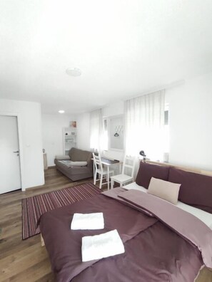 A modern, well-lit bedroom with a large bed, a desk, and a sofa. - Aria Plitvice (Plitvicka Jezera)