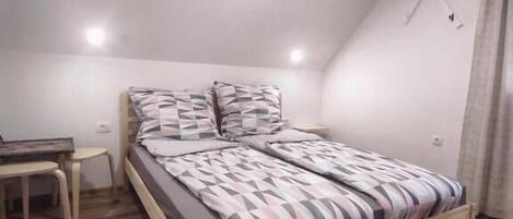 A bedroom with a wooden bed, a bedside table, a small desk, and a rug.