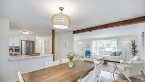 Una cucina moderna con un frigorifero in acciaio inossidabile, un tavolo da pranzo in legno con sedie bianche e un lampadario.