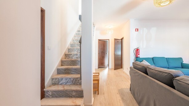 Ein modernes Interieur mit einer Marmortreppe, einer hölzernen Bank und einem grauen Sofa.