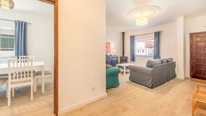 Ein Wohnzimmer mit einer Couch, einem Esstisch mit Stühlen und Holzboden.