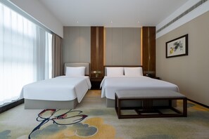 A hotel room with two beds, a bench, a nightstand, and a large window.